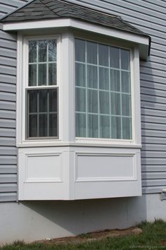 a white window sitting on the side of a gray house