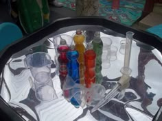 the tray is filled with many different colored bottles and glasses on it's glass table