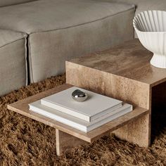 a coffee table with a book on it and a white vase sitting next to it