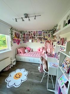 a child's bedroom decorated in pink and white with pictures on the walls, bedding, desks and shelves