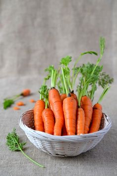 a basket filled with carrots sitting on top of a table next to parsley