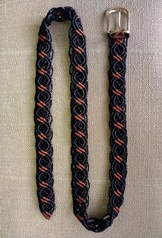 an orange and black rope with a metal buckle on it's end, sitting on a white surface