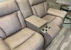 a reclining couch with two side tables on the back and one end facing it