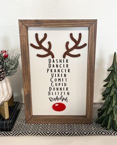 a framed poster with reindeer antlers on it next to a christmas tree and other decorations