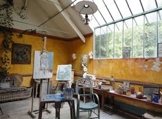 an artist's studio with yellow walls and paintings