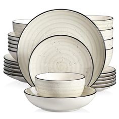 a set of white dishes with black rims and speckles on the plates