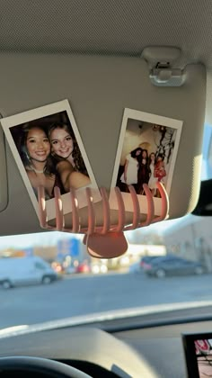 the interior of a car with two pictures hanging from it's dash board and one photo on the dashboard