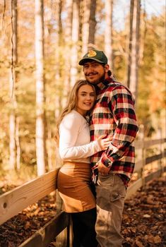 a man and woman standing next to each other on a bridge in front of trees