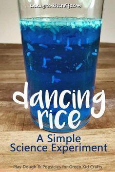 a glass filled with blue liquid sitting on top of a wooden table next to a sign that reads dancing rice