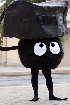 a man dressed up as a black bag with eyes and legs