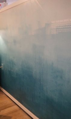 a man is standing in front of a wall with blue and green paint on it