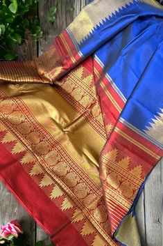 This stunning kanjivaram saree is handwoven in navy blue woven in ettu kol technique. The borders have an ettu kol temple reku woven in gold zari. The grand pallu in deep burgundy color features an ettu kol band in gold zari bordering with peacocks and traditional motifs. Approximate Length 6.5 mtrs (inclusive of blouse length) Approximate Height - 48 - 52" Approximate weight - 1.7 lbs Saree comes with fall, picot and tassels done when applicable. Blouse piece is cut. Kindly Note : The colors you see on your device may vary due to the color reproduction, brightness and resolution of individual devices. If you'd like more clarity before your purchase, please contact our support team. Royal Blue Zari Weaving Saree For Festivals, Royal Blue Saree With Zari Weaving For Festivals, Traditional Slub Silk Wear With Border, Festive Blue Saree With Border, Blue Dupatta With Border For Traditional Ceremonies, Saree With Zari Weaving For Traditional Ceremonies, Festive Saree With Border For Rituals, Blue Banarasi Silk Saree With Border, Raw Silk Saree With Weaving Work For Rituals