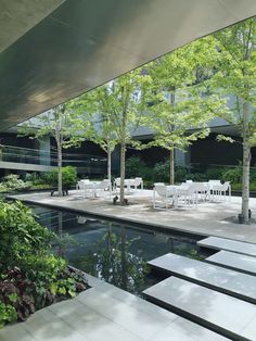 an outdoor patio with tables and chairs next to a pool in the middle of trees