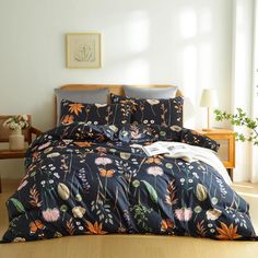 a bed covered in a black floral comforter and pillows next to a wooden table