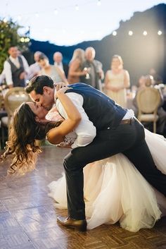 a bride and groom kissing on the dance floor