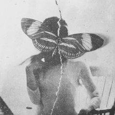 a black and white photo of a woman with a butterfly on her head