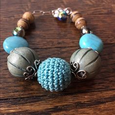 a close up of a bracelet on a wooden table with beads and beads around it