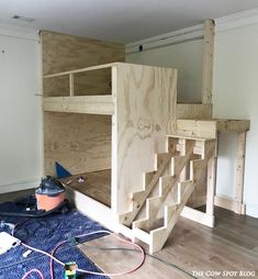 a wooden bunk bed sitting on top of a hard wood floor next to a wall