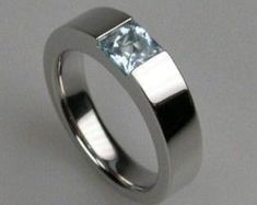 a white gold ring with a princess cut aqua blue topazte stone in the center