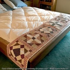 a bed with a quilt on top of it next to a book shelf and window