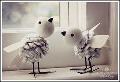 two birds made out of yarn sitting on top of a window sill next to each other