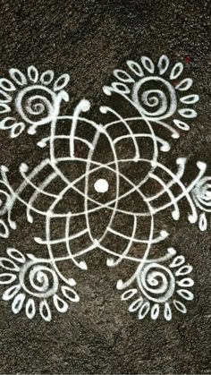 an intricate design is painted on the ground with white paint and black chalk, as if it were made from scratchsticks