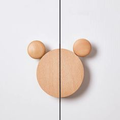 a wooden mickey mouse head hanging on the side of a white wall next to a black string