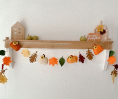 a wooden shelf with fall decorations hanging from it