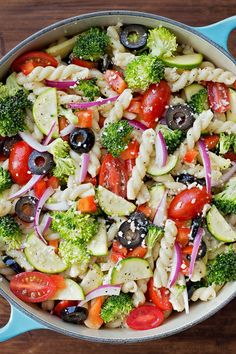 a pasta salad with tomatoes, broccoli, cucumbers and olives