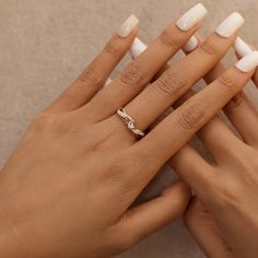 two hands holding onto each other with white manicured nails and a diamond ring on their fingers