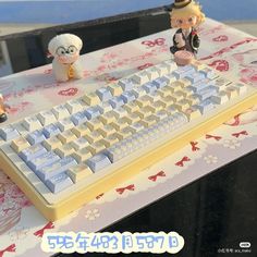 a computer keyboard sitting on top of a table with two figurines next to it