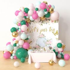 a table topped with balloons next to a sign that says let's party tea