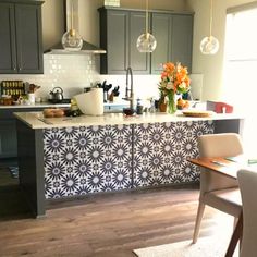 a kitchen with grey cabinets and an island in front of the countertop, along with a dining room table