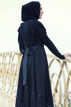 Experience a touch of sophistication with our specially designed abaya featuring a full circle skirt made from premium black Nahda fabric. The abaya boasts a high collar with three hidden clasps and a decorative trim that highlights two elegant shades of black. The included belt allows for adjustable fit, ensuring comfort and style. Please note that the white flowers visible in the images are part of the brand watermark and not the actual design. The trimming and belt design may vary slightly bu Elegant Black Abaya With Modesty Panel, Long Black Modest Khimar, Modest Black Khimar, Modest Black Abaya For Formal Occasions, Black Abaya With Modesty Panel For Eid, Black Long Abaya With Modesty Panel, Elegant Black Maxi Khimar, Black Long Modest Niqab, Elegant Black Maxi Length Khimar