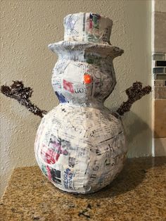 a snowman made out of newspapers sitting on top of a counter next to a wall