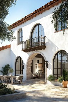 an outdoor patio area with tables and chairs next to a white stucco building that has arched windows