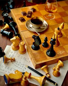 chess pieces on a wooden table next to a cup of coffee and some other items