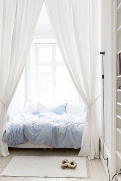 a bedroom with a bed, bookshelf and white curtains over it's windows