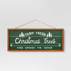 a green sign hanging from the side of a wall that says farm fresh christmas trees