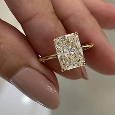 a woman's hand holding a ring with a yellow diamond in the center and two white diamonds on each side