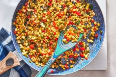 a pan filled with cooked corn on top of a table next to a wooden spatula