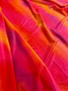 an orange and pink tie - dyed fabric is laying on top of a bed sheet