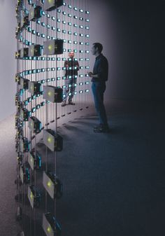 a man standing in front of a wall with lots of lights on it