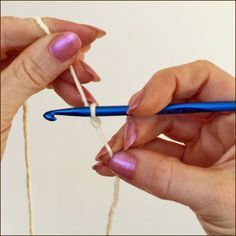 two hands holding blue crochet hooks with white yarn on them and one person knitting