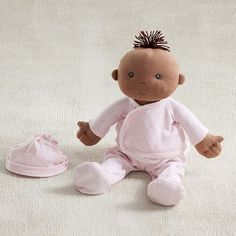 a baby doll sitting on the floor next to a pair of shoes