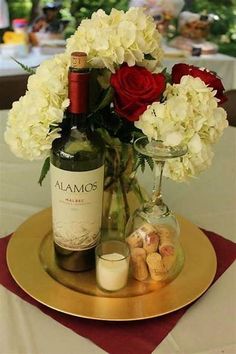 there is a bottle of wine and some flowers on the table with candles in it