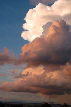 a large cloud is in the sky above some trees