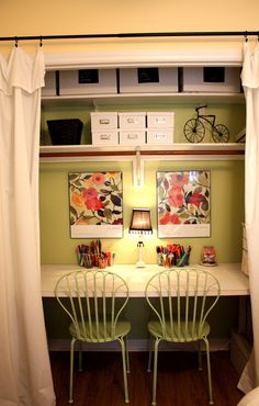 two green chairs sitting at a white desk in front of a wall with pictures on it