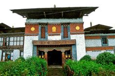 an old building with many windows and decorations on it's front door, surrounded by greenery