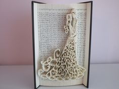 an open book with a paper cutout of a woman's dress on it